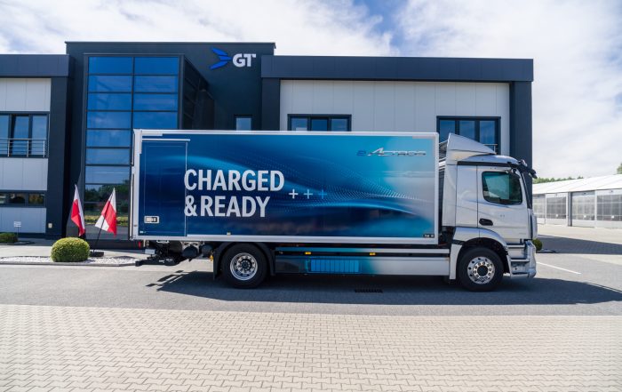Camion elettrico Mercedes-Benz eActros con allestimento GT Trailers parcheggiato davanti alla sede dell'azienda in Polonia. L'immagine rappresenta l'impegno per la mobilità sostenibile e la transizione verso il trasporto elettrico, in linea con la nuova partnership strategica tra Schmitz Cargobull e GT Trailers