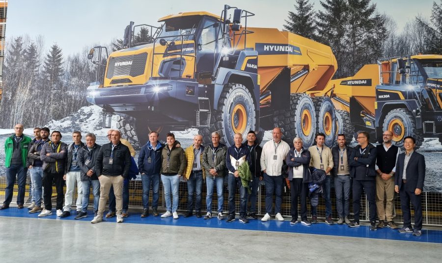 Gruppo di concessionari e clienti italiani Hyundai davanti al poster con dumper HA30A e HA45A durante l’evento Next Level a Tessenderlo.