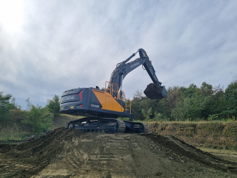 Escavatore Hyundai HX400L in movimento su terreno collinare durante test a Tessenderlo.